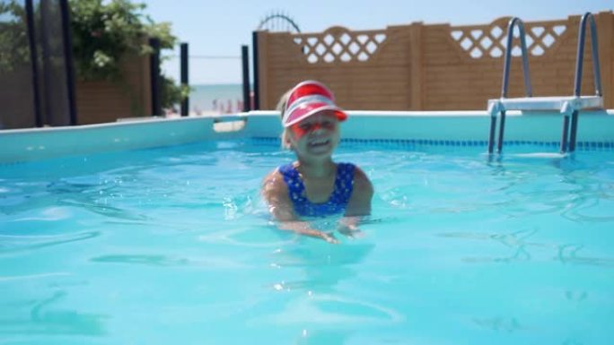 开朗的小女孩在带有蓝色透明水的游泳池里游泳。享受水上活动。酒店的暑假。