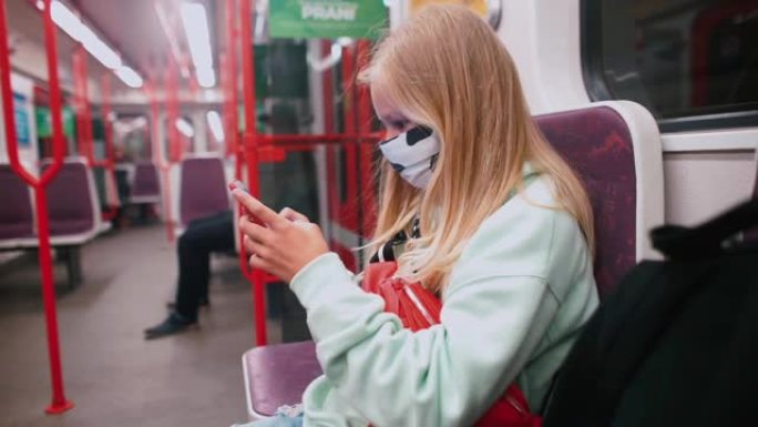 戴口罩的女孩在地铁车厢的社交网络上发帖。沟通