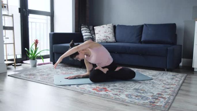 放松的女人坐在东方室内的地板上练习瑜伽练习。