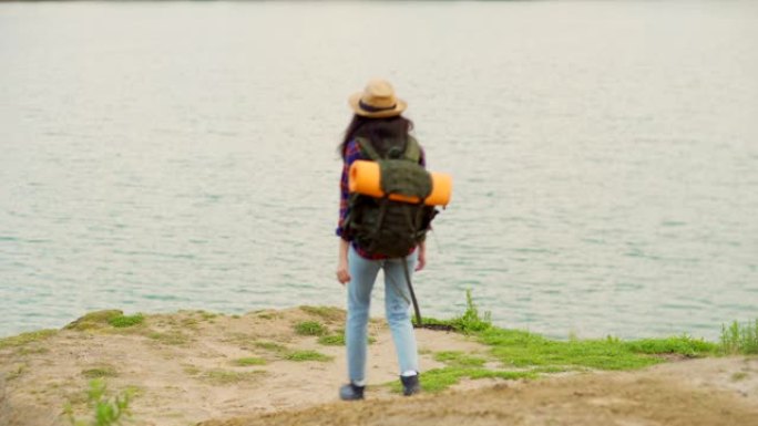 背靠背的女年轻徒步旅行者，背着背包走下坡路走向大海，欣赏美丽的景色