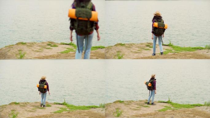 背靠背的女年轻徒步旅行者，背着背包走下坡路走向大海，欣赏美丽的景色