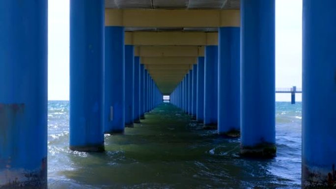 平行的蓝色圆柱之间的码头下的海，在水中形成狭窄的走廊。