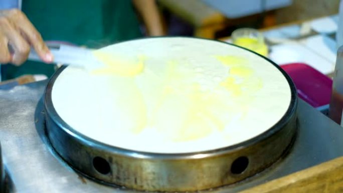 厨师将香蕉山药倒入牛奶可丽饼中。泰国街头美食。