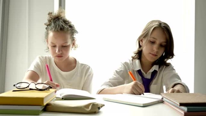 男生和一个女生坐在教室的同一张桌子上。男孩认真写，女孩从笔记本男孩那里注销