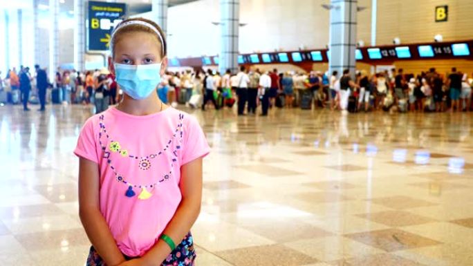 在机场，戴着医用防护面具的女童肖像，在登机柜台和带行李的航空乘客的背景下。冠状病毒疫情结束后，航班重