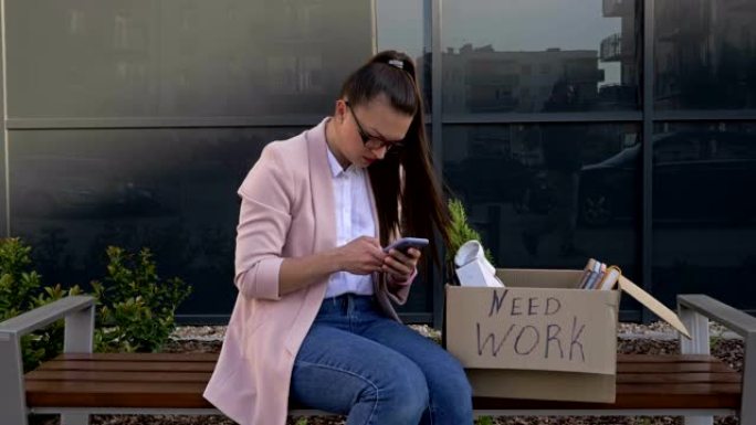 需要工作。办公室附近的长凳上坐着一个非常沮丧的年轻女子。在她手中是一个装有个人物品和手机的盒子。女人