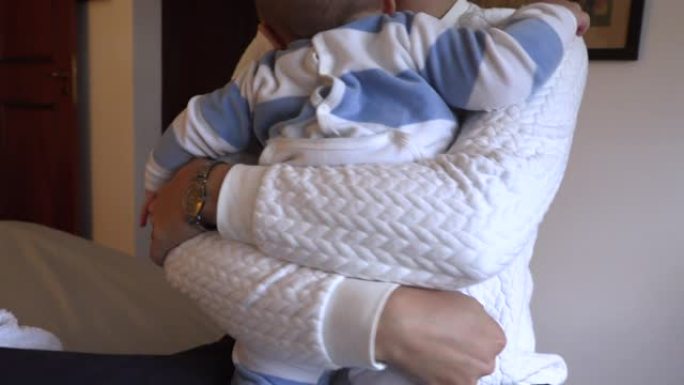 母亲拥抱蹒跚学步的婴儿。父母拥抱婴儿。包裹在蹒跚学步的手臂的特写镜头