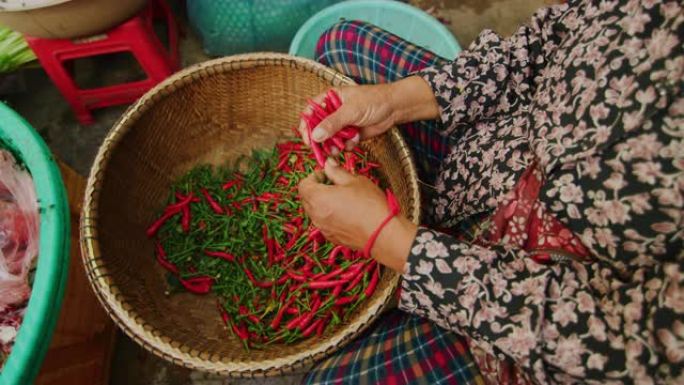 在柬埔寨金边，一名妇女在户外市场采摘红辣椒的慢动作60fps拍摄