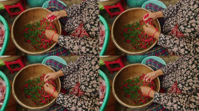 在柬埔寨金边，一名妇女在户外市场采摘红辣椒的慢动作60fps拍摄