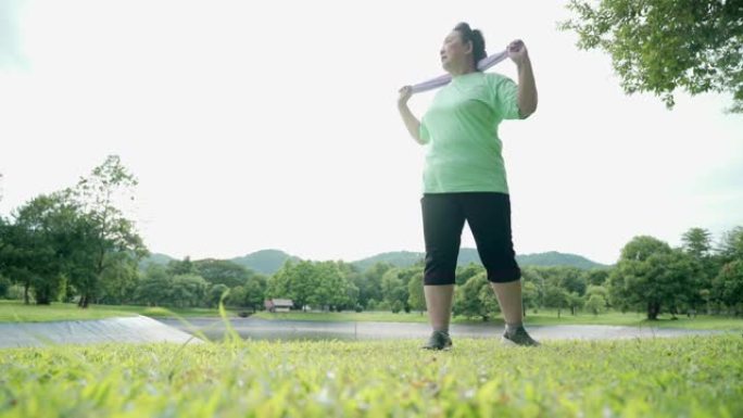 亚洲胖乎乎的高级女性在公园做站立热身运动，湖山翻身臀部充分伸展，退休后生活自理动力，保健理念，宽镜头