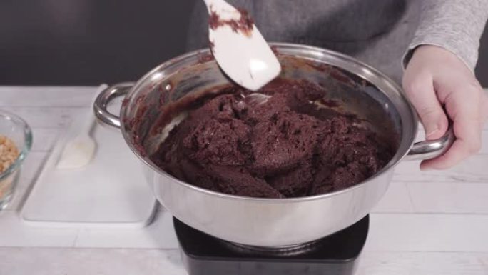 将巧克力片在烹饪锅中融化，制成澳洲坚果软糖。