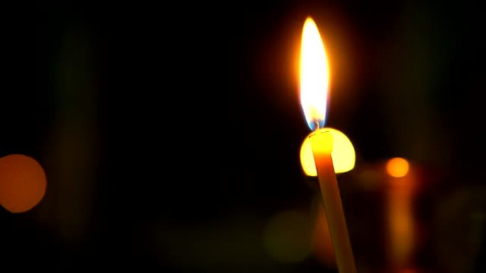 特写教堂蜡烛在黑暗中燃烧