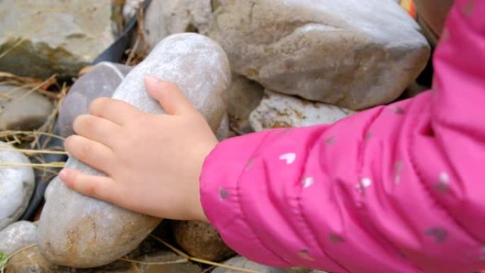 儿童用一块石头摩擦另一块石头的特写