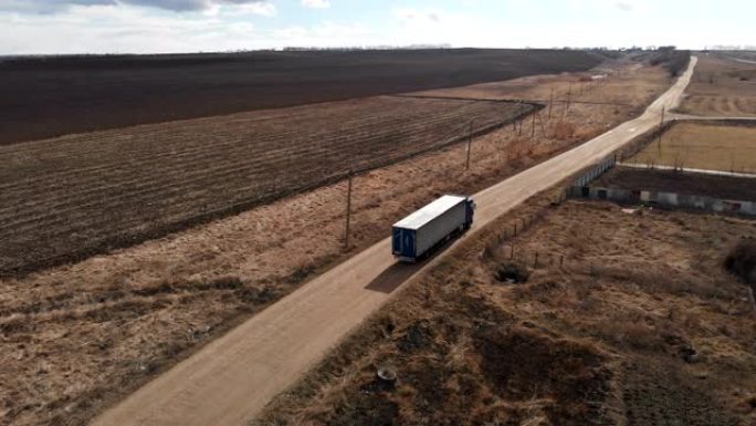 一辆大型卡车的鸟瞰图，一辆拖车沿着一条土路行驶，在郊区高速公路附近寻找掉头的地方。