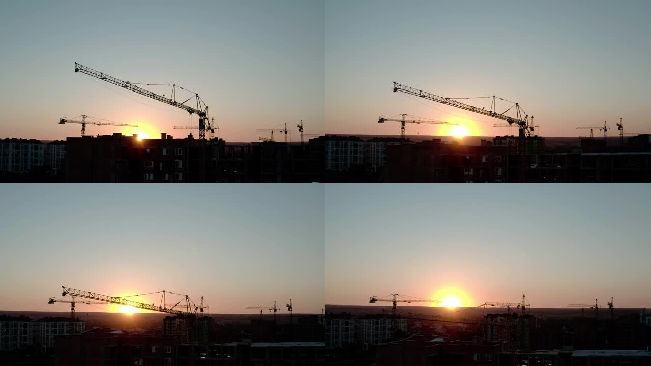 日落光下剪影建筑起重机的空中无人机视图。城市建筑工地。飞升V2