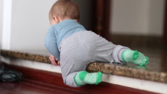婴儿第一次爬下台阶。学步婴儿学习爬下楼梯