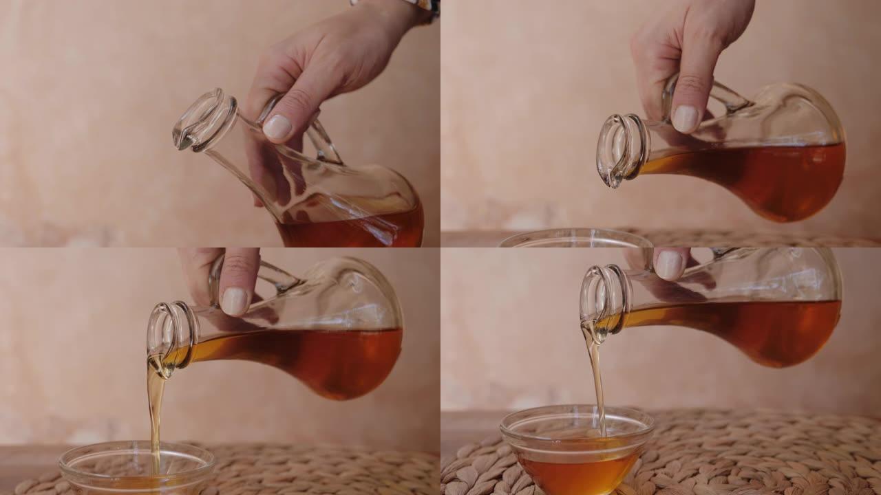 一个女人将摩洛哥坚果油倒入玻璃碗中。