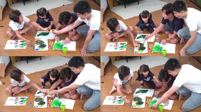 高角度视图: 父亲看着一群小孩坐在地板上，用水彩画在纸上画了一幅有趣的画。周末，老大哥和两个兄弟姐妹