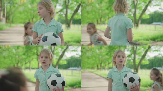 可爱的金发男孩带着足球对快乐的妹妹大喊大叫。不满的兄弟在阳光明媚的夏日公园与兄弟姐妹争吵。冲突，家庭