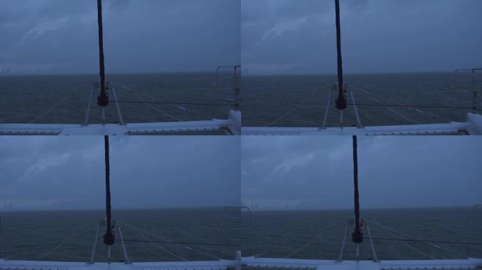 一艘帆船在阴暗的天气下在海中行驶，进入黑暗的朦胧地平线