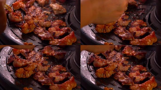筷子上的烤猪肉在热蒸汽上从热锅中抽出来的水，用于在聚会中烹饪，晚上烤肉的背景是人们在餐厅吃美味可口的