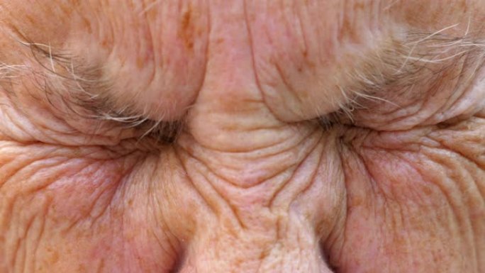 成熟女人的肖像强烈地拧起她的灰色眼睛，然后睁开。年迈的祖母皱着皱纹的脸看着镜头，表情惊讶。慢动作