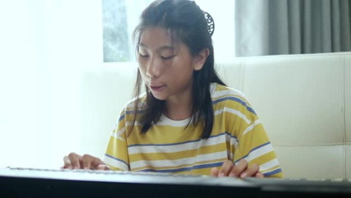 亚洲女孩在家玩窗户附近的键盘乐器，生活方式概念。