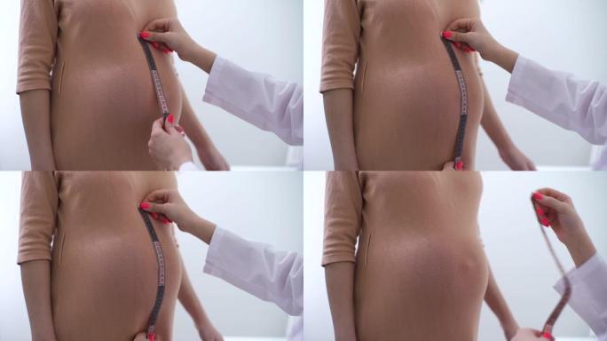 无法识别的专业女性医生的手特写测量孕妇的腰围