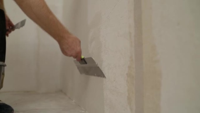 用刮刀把砂浆放在墙上。建筑商在墙上放了砂浆。石膏墙。外部饰面。