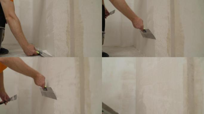 用刮刀把砂浆放在墙上。建筑商在墙上放了砂浆。石膏墙。外部饰面。