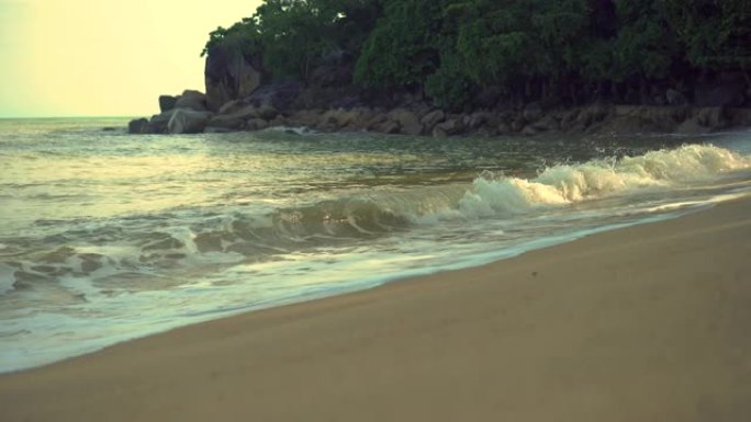 4k视频画面，海浪冲刷了热带海滩海水破裂的沙质顶部的脚印。