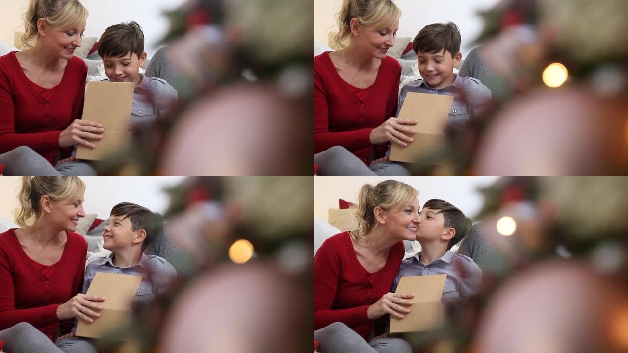 圣诞快乐，家庭幸福，儿子感谢圣诞节礼物，在客厅的照亮和装饰的树附近给妈妈一个吻