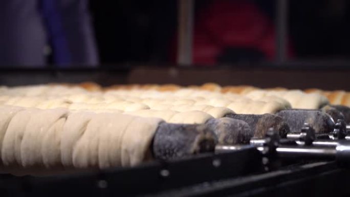 准备传统的捷克街头食品Trdelnik在圣诞节市场上的热煤上卷在木串上。涂有糖衣的面包卷，捷克共和国