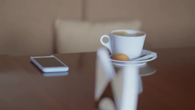 桌子上有咖啡和电话的杯子，等待他们的访客