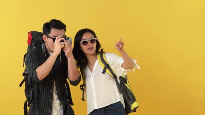快乐的亚洲旅游夫妇背包客在黄色背景上观光