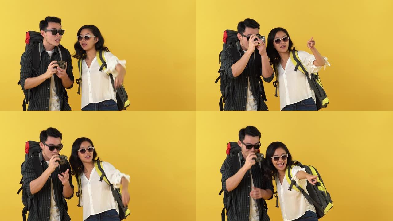 快乐的亚洲旅游夫妇背包客在黄色背景上观光