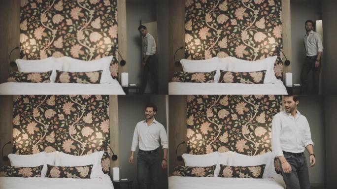 疲惫的男人进入豪华酒店的房间。性感的男人在现代卧室跳床