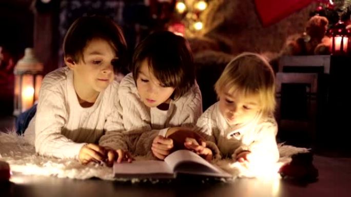 三个孩子，男孩兄弟，圣诞节晚上在家看书，躺在地板上