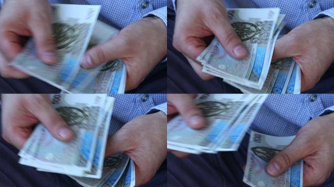 一个穿着商务衬衫的人数着波兰的钱。大量价值最高的纸币，500兹罗提