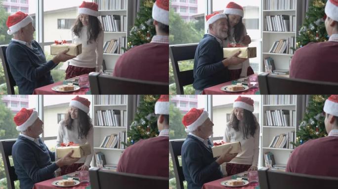 老人戴着红帽子，在圣诞节用餐时向家人赠送礼物或礼物