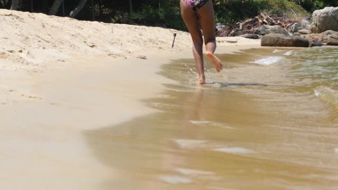 软焦点和焦点拍摄女子的腿在沙滩水边奔跑。
