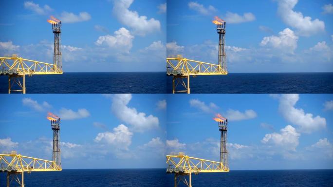 天然气火炬在海中油气海上平台上的慢动作燃烧具有蓝天的油气工业概念。