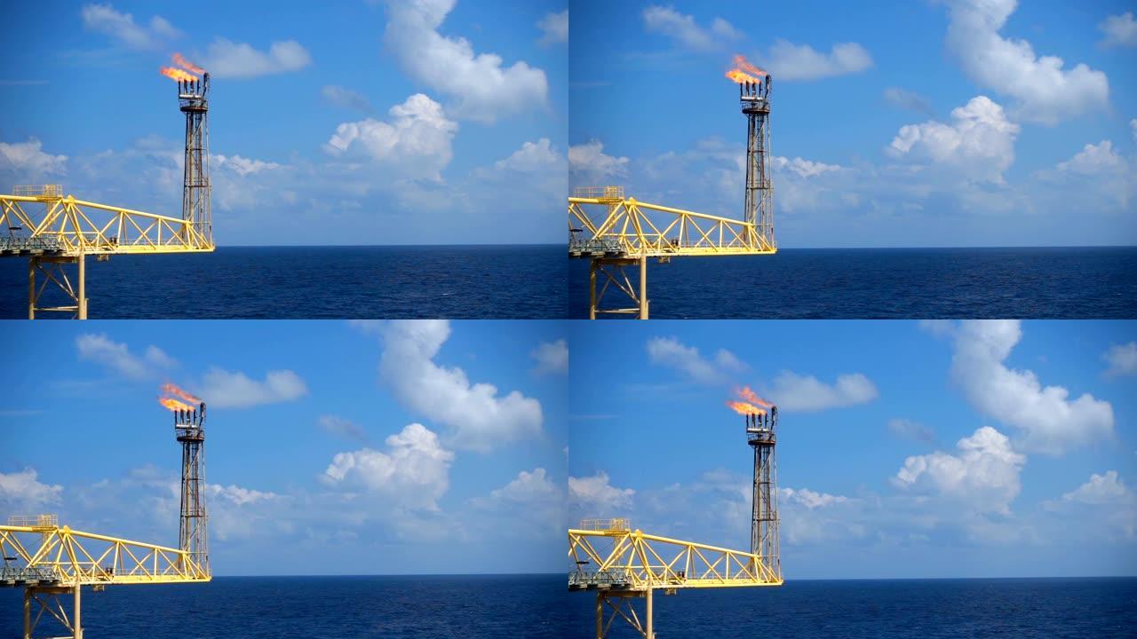 天然气火炬在海中油气海上平台上的慢动作燃烧具有蓝天的油气工业概念。