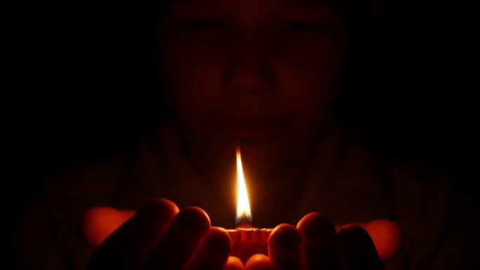 女孩手里拿着迪帕克印度油灯，看着火焰。黑色背景