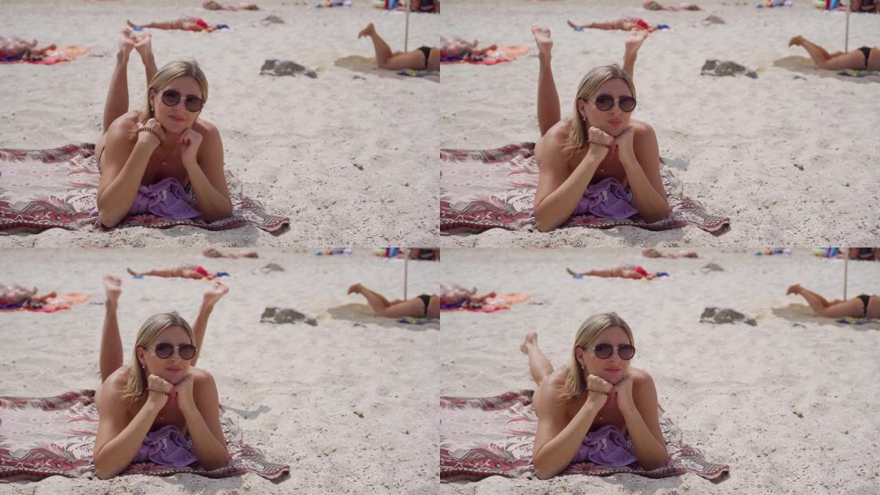 一个戴着眼镜的女人躺在沙滩上晒日光浴。她无忧无虑地休息着，双腿也会发生什么事。