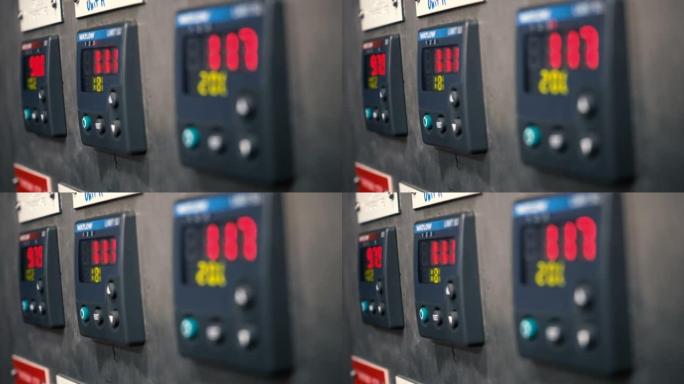 在巨大的空工厂车间或工业工厂中，带有许多彩色按钮的电表控制装置面板。