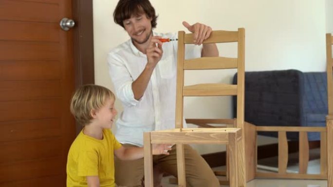 父亲和儿子用小零件组装木制家具。小男孩帮他父亲组装椅子。