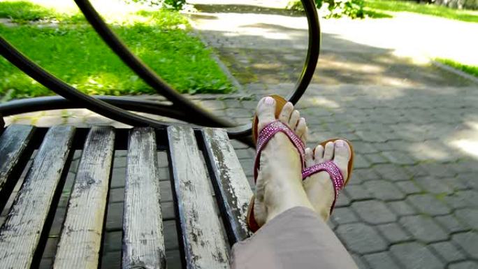 4 K，一个女人漫不经心地躺在公园的秋千上，享受大自然的休息，人字拖秋千的女人的脚