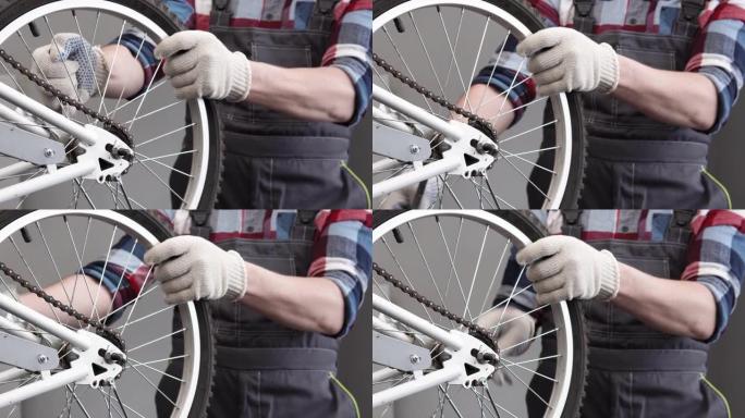 自行车的保养和修理。穿工装裤的人拧下后轮轴的螺母。