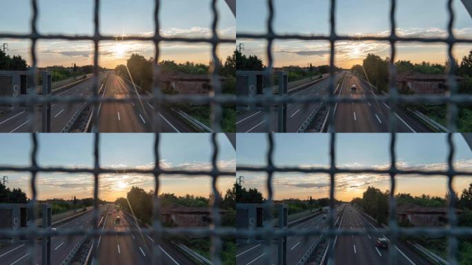 从道路安全铁丝网后面的立交桥拍摄的日落时高速公路的4k视频延时。